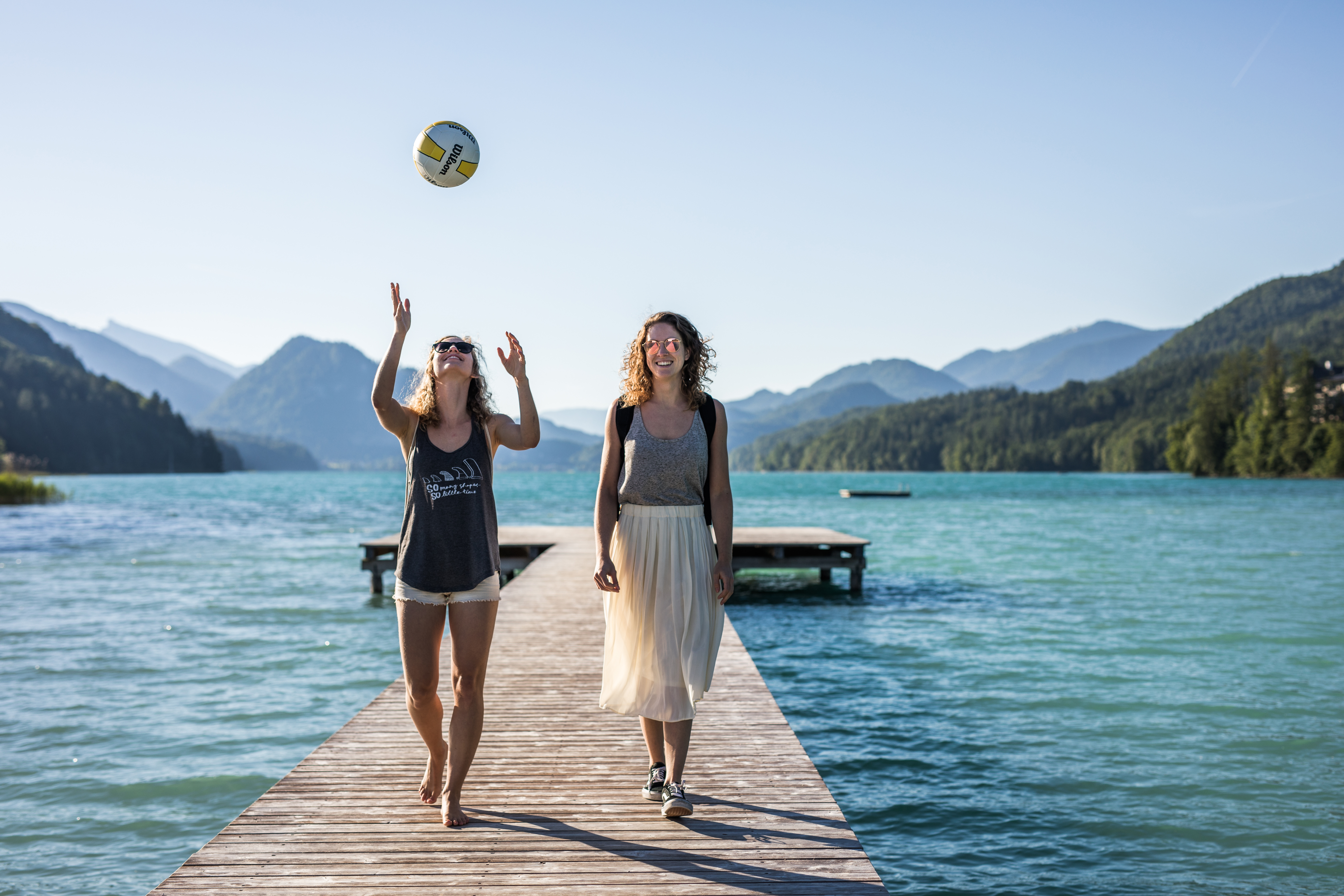 Mädchen spazieren am Steg mit Volleyball – Tourismusfotografie